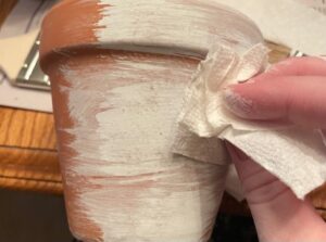 Wiping off excess paint with paper towel to whitewash terracotta