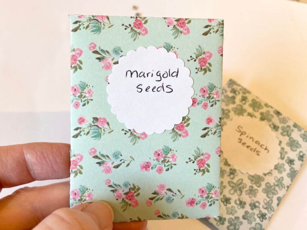 diy seed packet made from blue floral scrapbook paper with pink rosebuds and labeled marigold seeds
