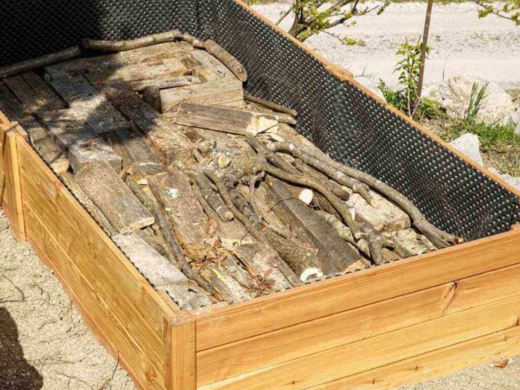 logs and sticks in the bottom of a raised bed